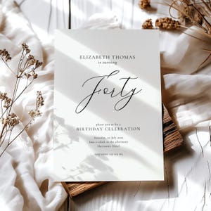 Può includere: Un biglietto d'invito bianco con una calligrafia elegante che annuncia una festa di compleanno. Il testo recita "Elizabeth Thomas compie quarant'anni". Ulteriori dettagli includono la data, l'ora e il luogo dell'evento. Sfondo strutturato.