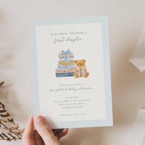 Może przedstawiać: Jasnoniebieskie zaproszenie z ząbkowaną krawędzią. Karta zawiera tekst "matthew thomas's first chapter" i "please join us for a fun-filled birthday celebration". Obecna jest również ilustracja misia i książek.