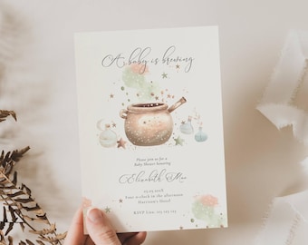 May include: A rectangular baby shower invitation card featuring the text A baby is brewing, Elizabeth Mae, 25.05.202X, Four o-clock in the afternoon, Harrison's Hotel, and RSVP 123 123 123. The design includes a brown cauldron, stars, and potions.