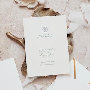 May include: A cream-colored rectangular Save the Date card featuring a black line drawing of a seashell at the top. The text reads: Save the Date for the wedding of Victoria Adams and Marcus James, 25 August 202X, Formal invitation to follow.