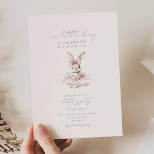 May include: A light pink invitation card with the text "our little bunny" and "ELIZABETH IS TURNING ONE". It features a watercolor illustration of a bunny wearing a pink bow and tutu. The card also includes party details.