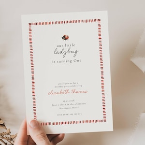 May include: A cream-colored invitation with a red dotted border and text. The invitation reads "Our little ladybug is turning One." Below, it says "please join us for a birthday party celebrating Elizabeth Thomas."