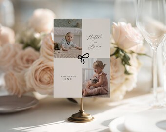 Puede incluir: Una tarjeta fotográfica rectangular sobre un soporte de metal dorado con dos fotografías de niños, un icono de lazo dibujado en línea negra y el texto "Matthew and Bianca" y "When we were ONE" impreso en fuente serif sobre fondo beige.