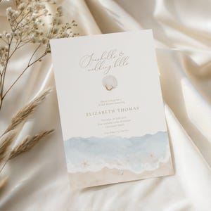 May include: A cream-colored invitation with the text "Seashells & Wedding Bells" and a seashell graphic. The invitation features a watercolor design of a beach scene with blue waves and sand. The invitation is for a bridal shower honoring Elizabeth Thomas.
