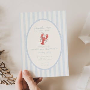 Peut inclure: Invitation d'anniversaire à rayures bleues et blanches. L'invitation présente un motif ovale avec une illustration de homard rouge et le texte "pinch me. I am one!" et les détails de la fête.