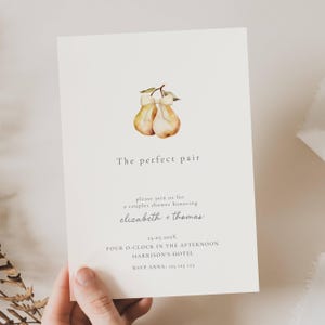 May include: A cream-colored invitation card with watercolor pears and the text "The perfect pair." The card invites guests to a couples shower honoring Elizabeth and Thomas, with the date, time, and location details.