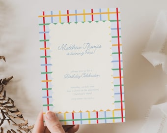 Op de afbeelding: Een verjaardagsuitnodiging met een kleurrijke geruite rand in rood, geel, blauw en groen. De uitnodiging heeft een geschulpte rand en de tekst "Matthew Thomas is turning One!" en "Birthday Celebration."