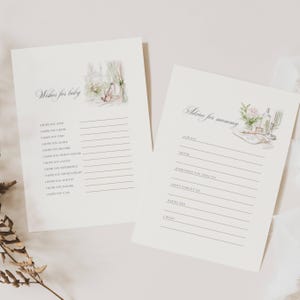 May include: Two cream-colored baby shower advice cards. One card reads "Wishes for baby" with a watercolor illustration of flowers and a window. The other card reads "Advice for mummy" with a similar illustration. Both cards have lined spaces for writing.