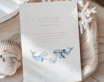 Op de afbeelding: Een uitnodiging voor een babyshower met de tekst "A LITTLE BOY IS ON THE WAY" en de namen Elizabeth & Marcus. De uitnodiging bevat aquarel illustraties van walvissen in blauwtinten. De uitnodiging heeft een witte achtergrond.