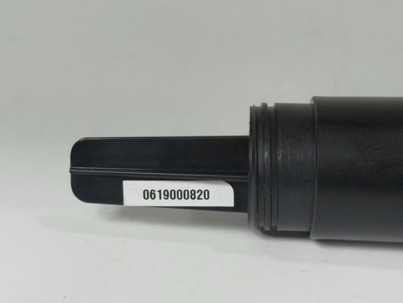 May include: A black plastic component with a rectangular paddle-like end and a cylindrical body. A white sticker with the number "0619000820" is affixed to the paddle. The object appears to be a part of a larger mechanism or device.