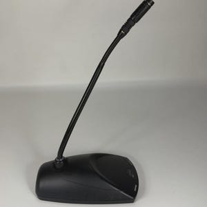 May include: A black desktop microphone featuring a long, flexible gooseneck stem attached to a sturdy, low-profile base. The microphone head is cylindrical with a small mesh grille, and the Shure brand name is printed on the base.