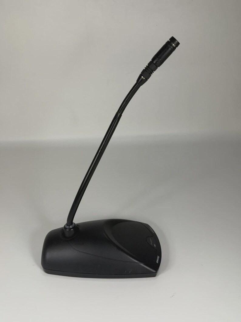 May include: A black desktop microphone featuring a long, flexible gooseneck stem attached to a sturdy, low-profile base. The microphone head is cylindrical with a small mesh grille, and the Shure brand name is printed on the base.