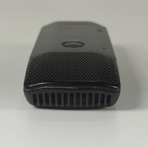 May include: A black rectangular digital voice recorder featuring a perforated speaker grille on the front, a central circular button, and a series of vertical vents along the bottom edge. The device has a smooth, matte finish with subtle branding.
