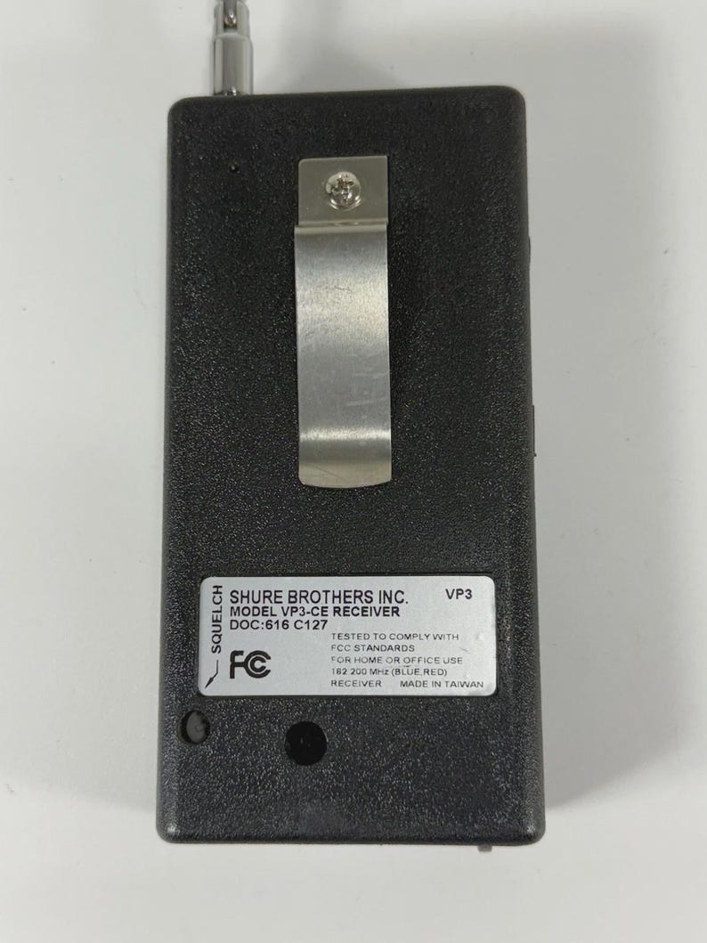 Puede incluir: Un receptor negro Shure Brothers Inc. VP3-CE con un clip met&aacute;lico y antena. El receptor tiene una etiqueta con texto que incluye "FCC STANDARDS" y "MADE IN TAIWAN".
