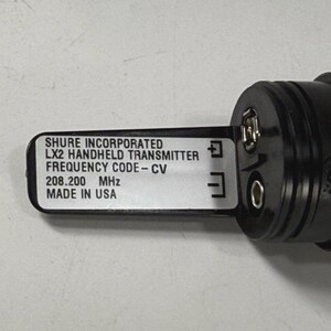 May include: A black Shure LX2 handheld transmitter with a label that reads "Shure Incorporated, LX2 Handheld Transmitter, Frequency Code-CV, 208.200 MHz, Made in USA."