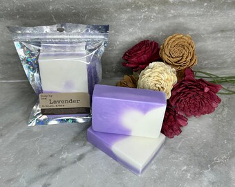 May include: Two bars of handmade lavender soap, one white with purple swirls and one purple with white swirls, in a clear plastic bag with a label that reads "Soap by Sam Lavender 5 oz Weight & Scent".
