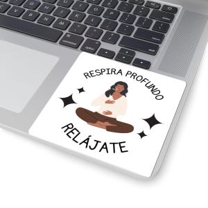 May include: A white sticker on a laptop featuring a seated figure in a meditative pose. The sticker has the words "RESPIRA PROFUNDO" and "RELAJATE" in a circular design, with black starbursts. The figure is wearing a white top and brown pants.