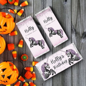 May include: Three pink and purple Halloween-themed chocolate bar wrappers with a skeleton unicorn design. The wrappers say "Holly is turning twelve" and "Holly's Birthday".