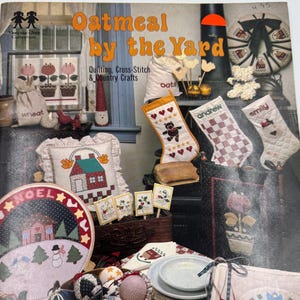 Peut inclure: Une collection d'artisanat campagnard et de projets de courtepointe. L'image présente des bas de Noël, des assiettes décoratives et un seau en métal rempli d'ornements en tissu. La couverture du livre indique "Oatmeal by the Yard".