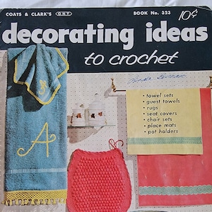 May include: Vintage book cover titled "Decorating Ideas to Crochet" featuring a bathroom set. The set includes blue towels with yellow trim and the letter "A", a red crocheted rug, and a matching wastebasket. The cover also lists items like towel sets and place mats.