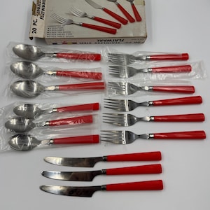 Puede incluir: Un juego de cubiertos de acero inoxidable de 20 piezas con mangos rojos. El juego incluye tenedores, cuchillos y cucharas, empaquetados en plástico y una caja de cartón. La caja dice "20 PC. STAINLESS STEEL FLATWARE".