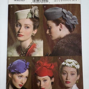 May include: Vogue Accessories sewing pattern V8008 featuring five hat designs. The patterns include a light beige pillbox hat with a fabric flower, a grey pillbox hat with a large floral accent, a purple hat with bows, a red hat with netting, and a white floral hat.