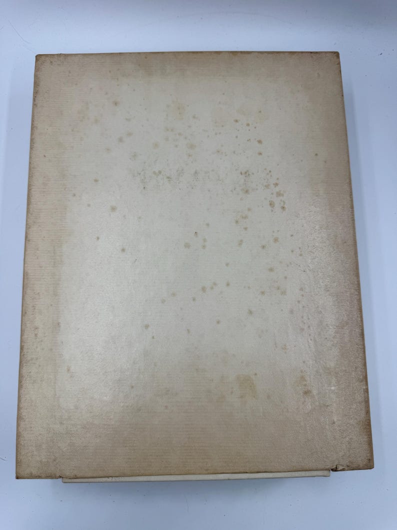 May include: A rectangular, off-white book with a worn appearance. The cover shows signs of age with brown spots and discoloration, suggesting it is vintage or antique. The edges are slightly worn.