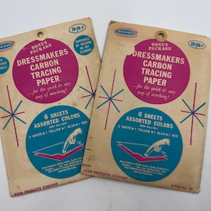 May include: Two vintage packages of Penn Dressmakers Carbon Tracing Paper. Each package features a pink circle with text, a blue circle with a sewing illustration, and starburst designs. The packages contain six assorted color sheets.