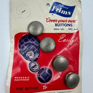 May include: Vintage "Prims Cover-your-own Buttons" package. The card features five metal buttons and a red and white design with blue plaid button examples. The package text includes "Washable Rustproof" and "Five Buttons".