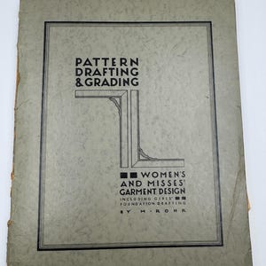 May include: A vintage book cover in a muted grey-green hue, featuring the title "Pattern Drafting & Grading" in black. The cover includes the text "Women's and Misses' Garment Design" within a black border.