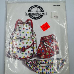 May include: A Frostline USA Dakota Station sewing pattern envelope titled Funsacks, featuring illustrations of a white backpack with colorful balloons, a red sports-themed bag, and a multi-colored checkered fanny pack in a clear plastic bag.