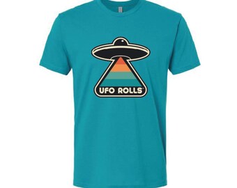 May include: Teal t-shirt featuring a retro-style graphic of a UFO with the text "UFO ROLLS" in a rounded font. The UFO design includes a black saucer, a triangular shape with orange and teal stripes, and a white outline.