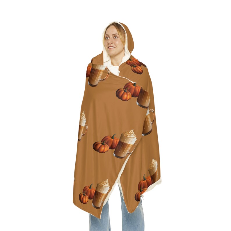 Puede incluir: Una manta con capucha en un tono marr&oacute;n c&aacute;lido, adornada con un patr&oacute;n repetido de calabazas y bebidas de caf&eacute;. El forro interior es de un material suave de color crema. Esta acogedora manta es perfecta para el oto&ntilde;o.