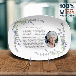 May include: White oval serving platter with a lavender floral design and a handwritten chocolate chip cookie recipe. A framed photo of a woman is in the center of the platter.