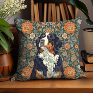 Puede incluir: Una almohada con un patrón floral y una ilustración de un perro de montaña bernés. El perro mira hacia la derecha y tiene un pelaje blanco, negro y marrón. El patrón floral está en tonos de naranja, amarillo y verde.