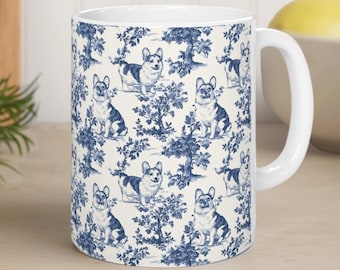 May include: A white ceramic mug featuring a repeating blue toile pattern of Corgi dogs interspersed with trees and foliage. The mug has a cylindrical body and a curved handle on the right side, showcasing a detailed monochromatic illustration.