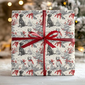 May include: A wrapped gift with a festive design. The wrapping paper features a repeating pattern of black and white dogs, red bows, and winter scenery. A red ribbon and bow secure the gift, perfect for the holiday season.
