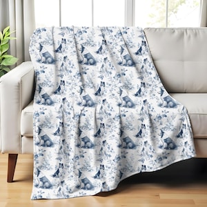 May include: A white fleece throw blanket with a repeating pattern of blue dogs and floral designs.