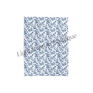 May include: A white and blue patterned blanket featuring a repeating design of dogs and floral elements. The design is reminiscent of classic toile patterns, with a detailed illustration of dogs in a natural setting.
