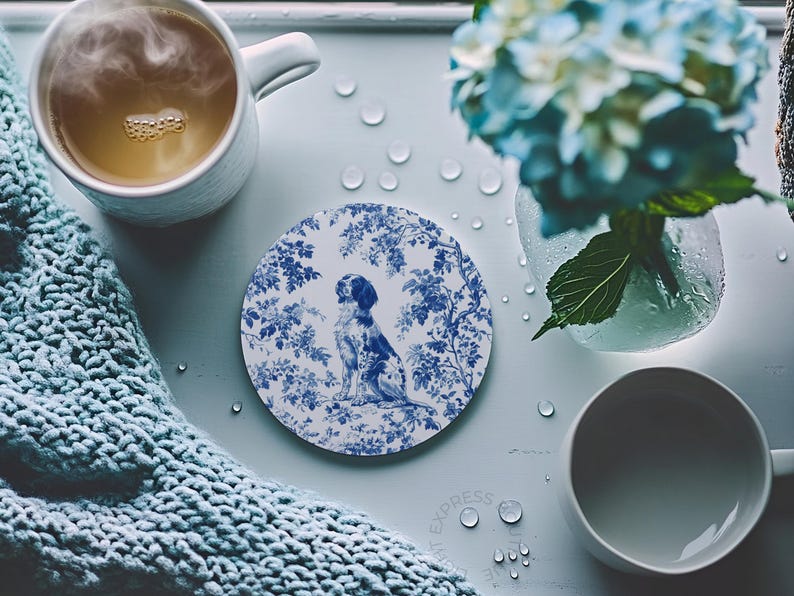 Peut inclure: Un dessous de verre en c&eacute;ramique blanche avec un motif floral bleu et blanc repr&eacute;sentant un chien. Le dessous de verre est rond et poss&egrave;de un bord sur&eacute;lev&eacute;.