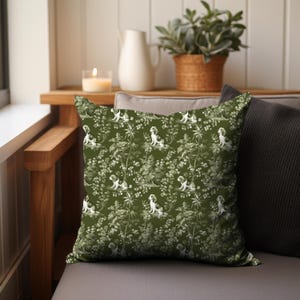 May include: A green throw pillow with a white and green pattern of dogs and foliage. The pillow is sitting on a couch.