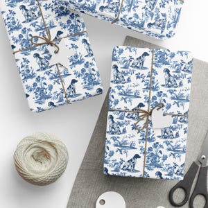 May include: Several wrapped gifts with a blue and white toile pattern featuring dogs and floral elements. The gifts are tied with twine and have blank tags. A ball of twine and scissors are also visible.