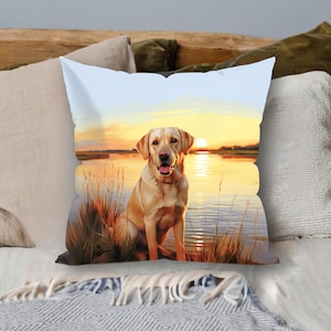 May include: A throw pillow featuring a golden retriever dog sitting in a field of tall grass at sunset. The dog is looking directly at the camera with a happy expression. The background is a blurry image of a lake and trees.