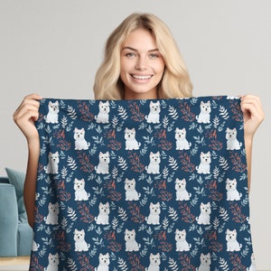 Op de afbeelding: Een blauwe stof met een patroon van witte West Highland White Terrier honden. De stof heeft een herhalend patroon van honden met rode en blauwe bloemmotieven.