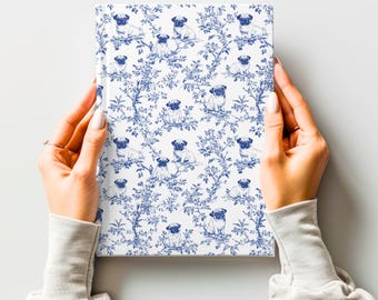 Puede incluir: Una libreta blanca con un patrón azul y blanco de carlinos y flores. Los carlinos están en posición sentada y las flores son estilizadas.