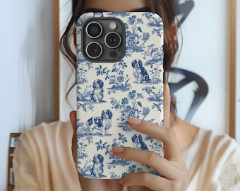 Puede incluir: Una funda de teléfono blanca con un patrón azul y blanco de perros y flores. La funda tiene un recorte para la cámara y una parte posterior transparente.
