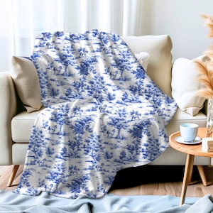 Könnte beinhalten: Weiße Wurfdecke mit einem blauen und weißen Toile-Muster mit Pferden und Bäumen.