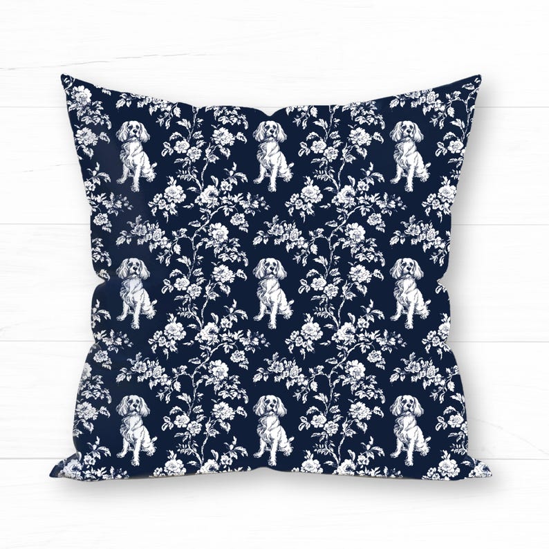 May include: Square throw pillow with a navy blue background and a white floral and dog pattern. The design features repeating images of dogs and floral elements, creating a decorative and stylish look. The pillow is a square shape.