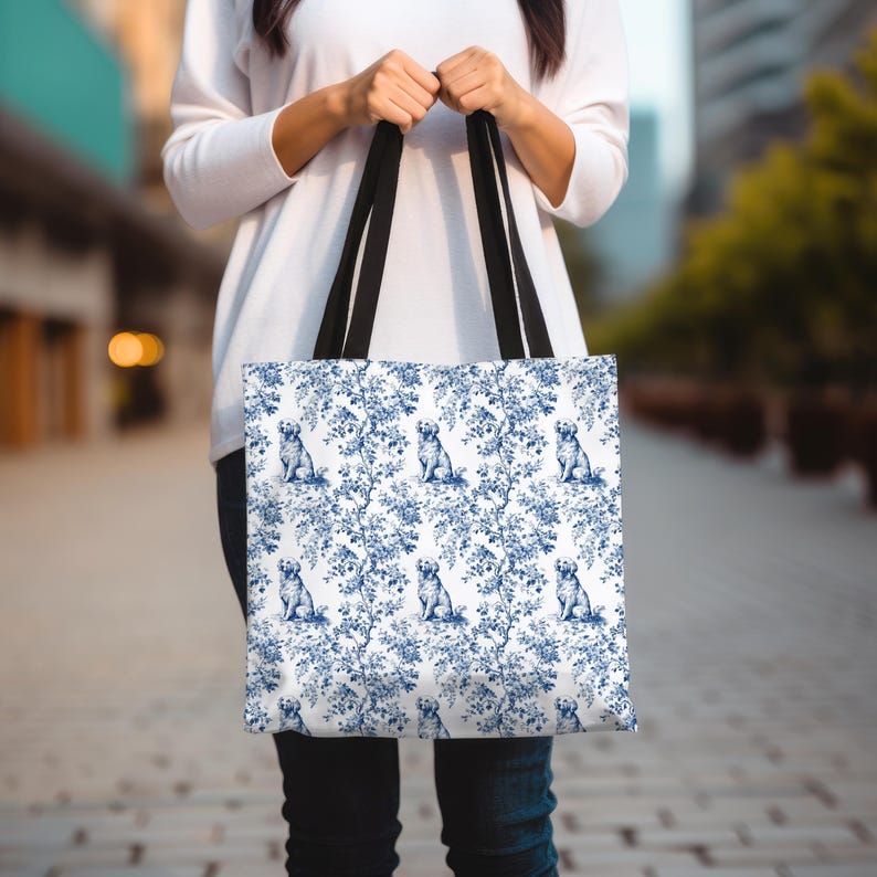 May include: A white tote bag with a blue and white pattern of dogs and floral designs. The bag has black handles.