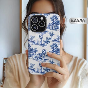 Könnte beinhalten: Eine weiße iPhone-Hülle mit einem blauen und weißen Toile-Muster mit Hunden. Die Hülle hat ein MagSafe-Logo auf der Rückseite.